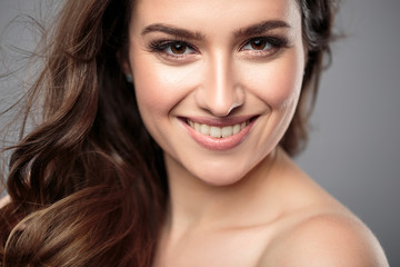 Obraz premium Brunette girl with healthy curly hair and natural make up . Beautiful model woman with wavy hairstyle .Care and beauty