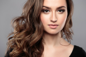 Fototapeta premium Brunette girl with healthy curly hair and natural make up . Beautiful model woman with wavy hairstyle .Care and beauty