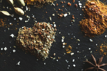 hearts made of selection of herbs spices and  sea salt on stone dark background, Indian spices, flat lay