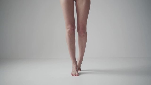 slender female legs close-up. girl standing on tiptoe on a light background