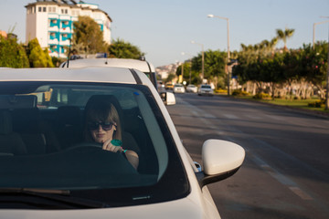 Young woman driving a car in the city. Portrait of a beautiful woman in a car. Travel and vacations concepts. Happy woman inside a car driving in the street. 