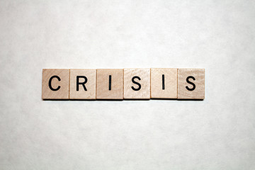 The word Crisis written in black letters on wooden blocks on a white background.