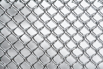 Background or pattern of frozen wire fence during winter, covered with snow and ice 