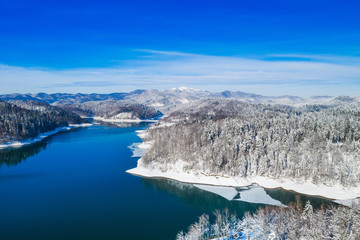Obraz premium Croatian nature landscape in winter, panorama of Lokvarsko lake and woods under snow in Gorski kotar and Risnjak mountain in background from drone 