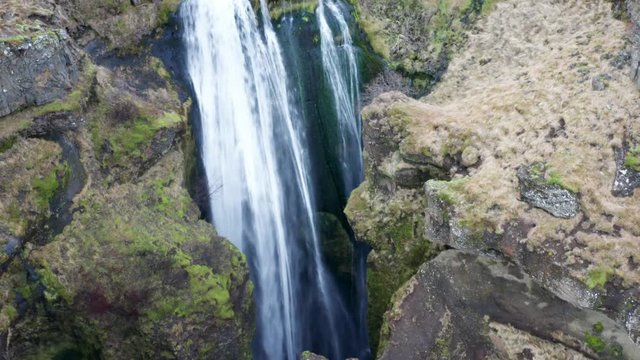 Aerial view of the scenic waterfall Gljufrabui in Iceland. Copter move away from the turbulent flow of water. 4k