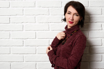 Beautiful woman posing near white brick wall background