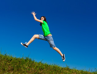 Fototapeta premium Girl jumping, running against blue sky