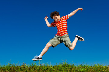 Fototapeta na wymiar Boy jumping, running against blue sky