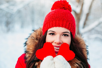 Beautiful young woman holding a red heart in the hands in winter park. Winter time.