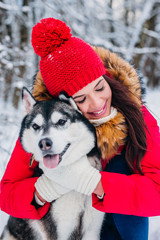 Woman caresses the Husky dog in winter forest