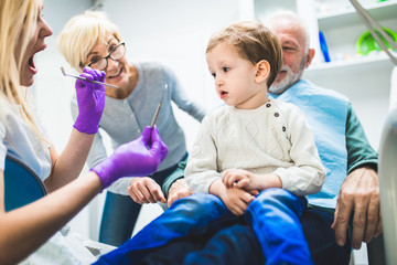 Two years old boy with his grandfather and grandmother first time on dental chair