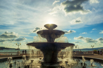 Fototapeta na wymiar Fountain on seaside promenade in sunny summer day