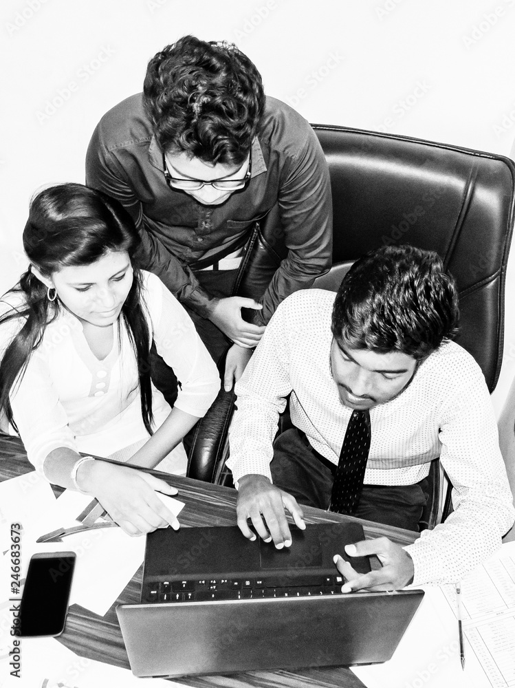 Wall mural Team of two young men and one indian woman in the office