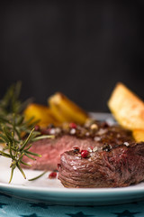 Beef steak with fried potatoes and rosemary in a bowl on a white plate with stars.