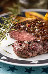 Beef steak with fried potatoes and rosemary in a bowl on a white plate with stars.