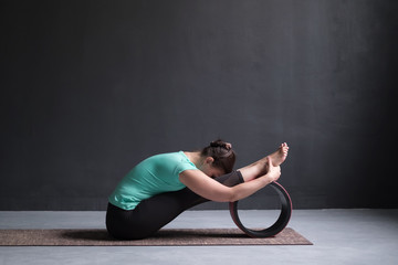woman practicing yoga, Seated forward bend pose, working out, using wheel