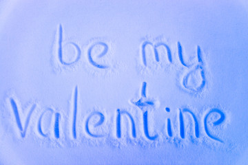 the phrase "be my valentine" written in the snow