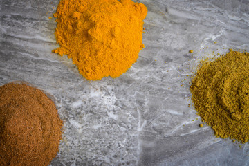 Turmeric, cayenne pepper and cumin seed powders on a marble worktop background