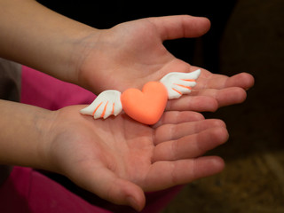 Pink heart with wings in the hands Love Carry Valentine