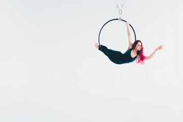 A young girl performs the acrobatic elements in the air ring. Studio shooting performances on a white background. © Евгений Вершинин