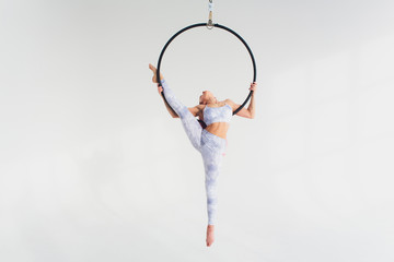 Aerial acrobat in the ring. A young girl performs the acrobatic elements in the air ring.