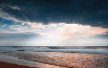 Amazing sunset on the ocean. Waves of the Atlantic ocean on the Guincho beach. Dramatic cloudy sky and reflection of the sunlight on water. Atlantic coast.Lisbon.Sintra-Cascais natural park. Portugal.