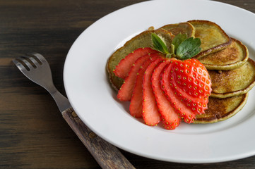 Vegetarian pancakes with ripe strawberries. on a wooden table.