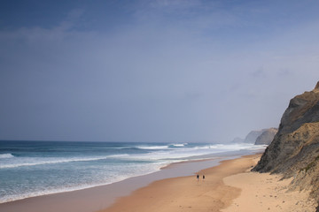 Praia da Bordeira in Carrapateira, Algarve, Portugal. Couple walking on the beach together watching the waves.