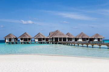 Water villas on the clear blue beach in the Maldives