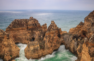 Sunrise over the ocean with the pillars and arch made of stone in Lagos, Algarve, Portugal. Long exposure showing the movement of the water at this popular tourist destination. 