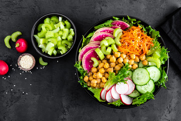 Salad Buddha bowl with fresh cucumber, celery, watermelon radish, raw carrot, lettuce, radish and chickpea for lunch. Healthy vegetarian food. Vegan vegetable dish. Top view
