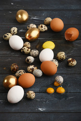 Different size quail and chicken eggs on a wooden surface. Vertical.