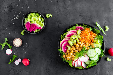 Salad Buddha bowl with fresh cucumber, celery, watermelon radish, raw carrot, lettuce, radish and chickpea for lunch. Healthy vegetarian food. Vegan vegetable dish. Top view