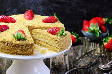 Honey cake with strawberry on the cake stand. Homemade cake cut and slice
