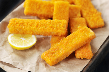 fried breaded fish sticks and lemon on paper