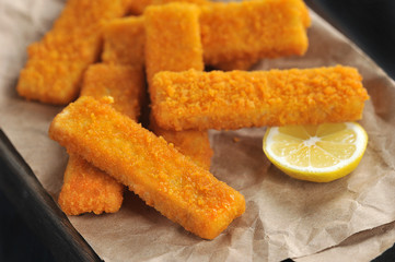 fried breaded fish sticks and lemon on paper
