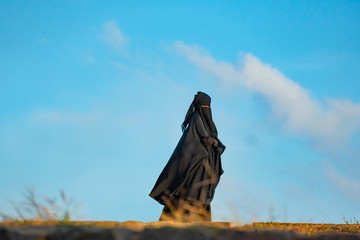 Muslim Woman In Black yashmak Against Blue Sky