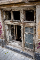 Fototapeta na wymiar Open ground floor broken wooden window of abandoned house in downtown district in Sofia, Bulgaria, moody autumn day as seen from city street