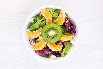 VISTA CENITAL DE BOL CON ENSALADA DE FRUTA SOBRE FONDO DE MADERA CLARA