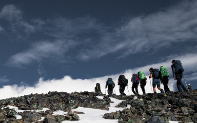 Group of people in a line hiking up the highest mountain in Sweden, Kebnekaise during a climb to reach the peak. 