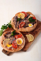 Two small pizzas on fried dough with sprats and egg two birds
