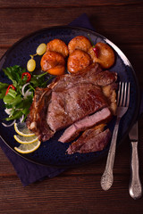 Beef steak on a plate with grilled apricots, lemon, hot pepper and grapes
