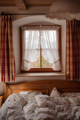 Fototapeta na wymiar Window with checkered curtains and wooden bed