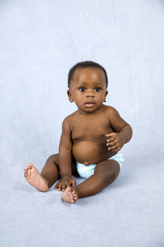 Sitting Up Adorable African American Baby Boy On A Grey Background