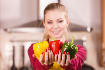 Happy woman holding bell peppers paprika