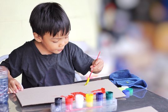 Kid and education concept, In the classroom, a student child boy drawing and painting colors on the paper. 