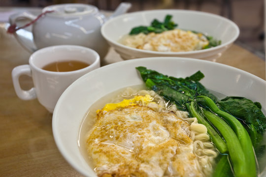 Traditional breakfast, noodle soup with egg and bok choy served with tea
