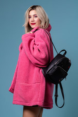 Fashion studio portrait of blonde girl with black backpack