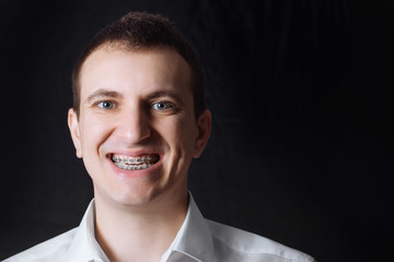 Portrait of a man of Caucasian appearance in orthodontic braces, metal brackets on his teeth in a...