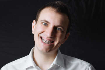 Portrait of a man of Caucasian appearance in orthodontic braces, metal brackets on his teeth in a...